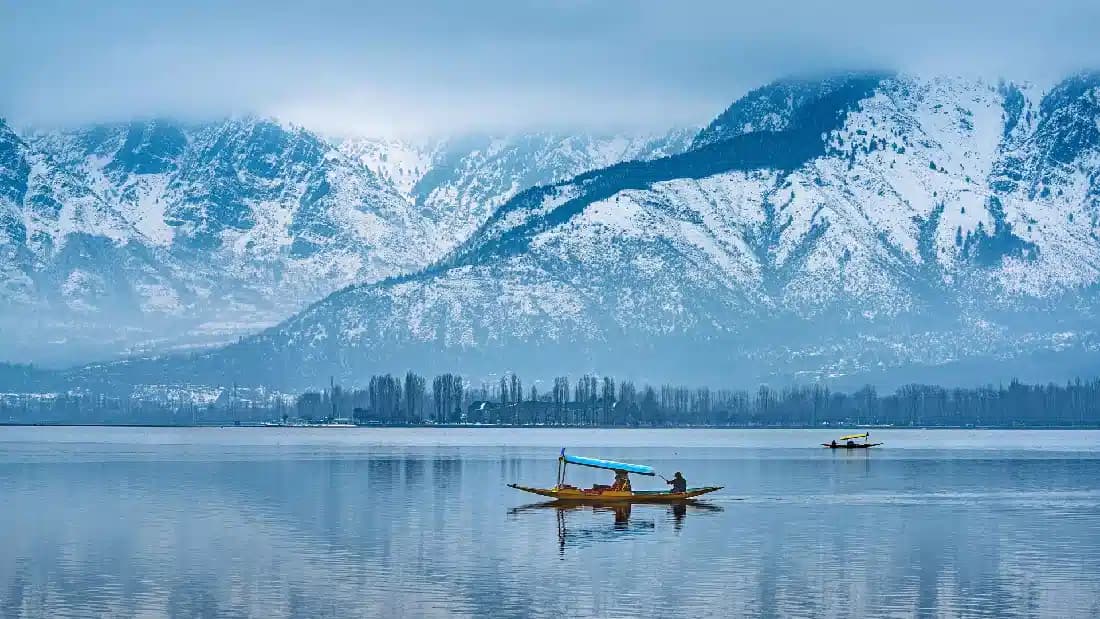Dal Lake at golden hour with shikara boats and the Zabarwan mountains reflected in the water